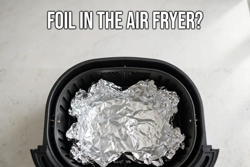 Crumpled aluminum foil inside an air fryer basket on a light countertop